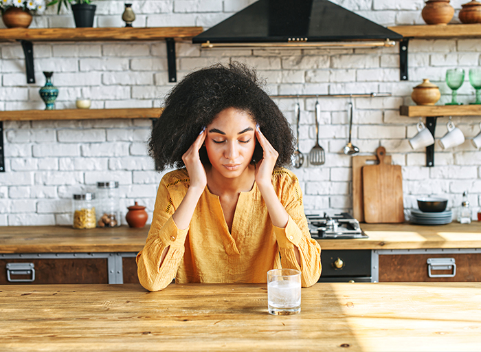 Woman alone at her kitchen table late at night, exhausted