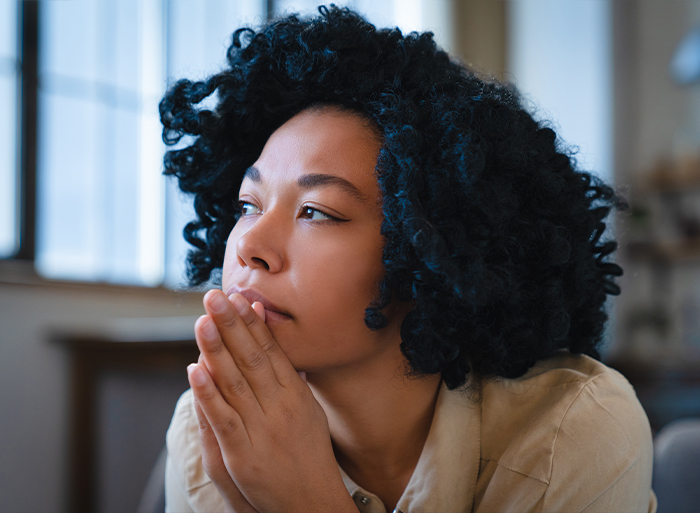 Woman with eyes closed in quiet distress at a table