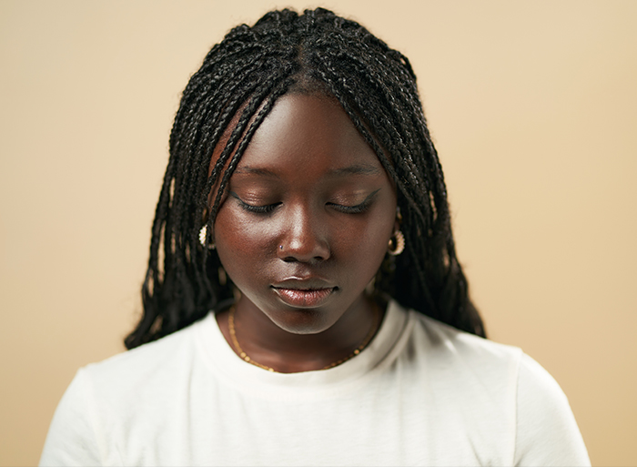 Young woman with braided hair, eyes downcast in contemplation